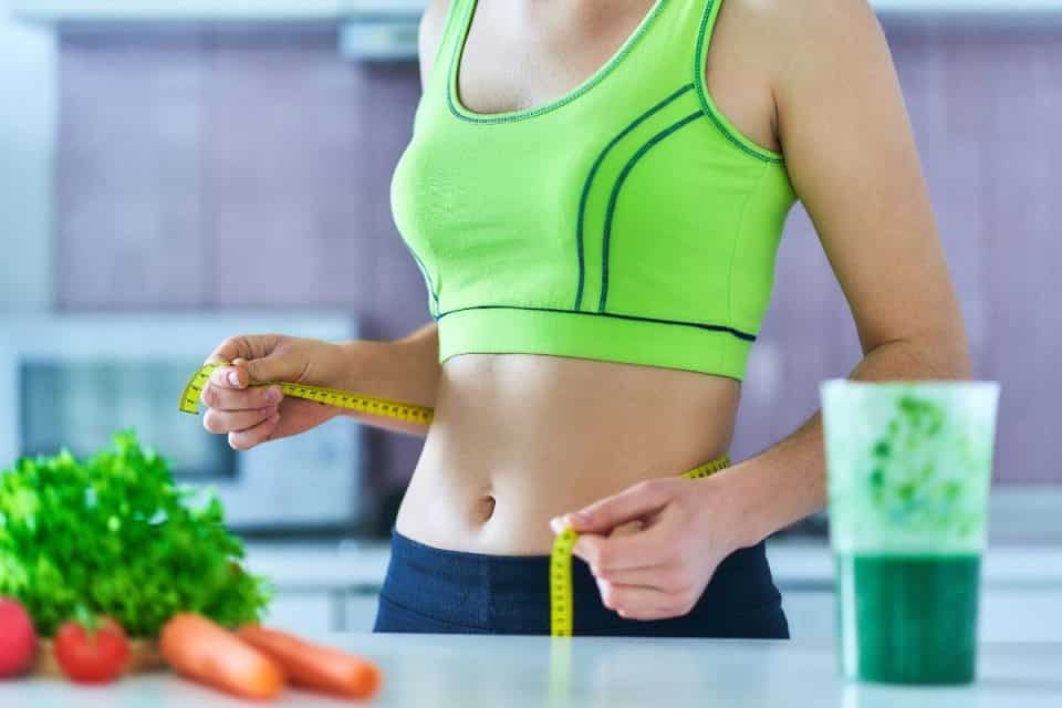 Uma mulher medindo a cintura depois de saber como emagrecer rápido e perder barriga