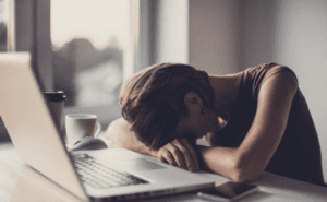 Pessoa deitada no notebook com cansaço excessivo
