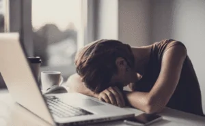 Pessoa deitada no notebook com cansaço excessivo
