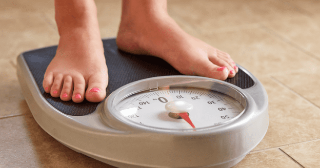Uma pessoa se pesando para encontrar uma maneira de perder peso rápido