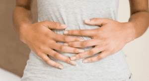 Uma pessoa com a mão na barriga precisando descobrir o que é bom para gases