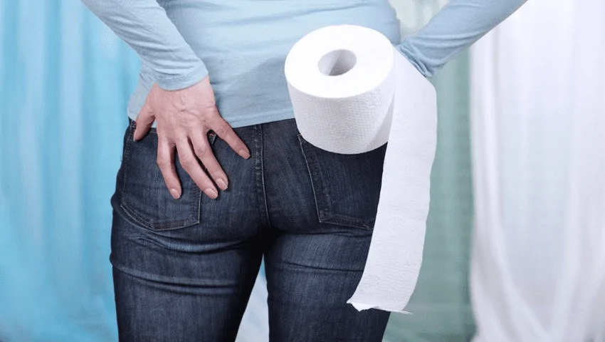 Uma pessoa segurando o papel higiênico e precisando de uma pomada para hemorroidas