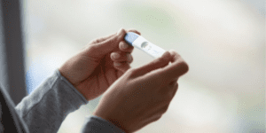 Uma pessoa segurando um teste de gravidez depois de sentir sintomas de gravidez