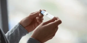 Uma pessoa segurando um teste de gravidez depois de sentir sintomas de gravidez