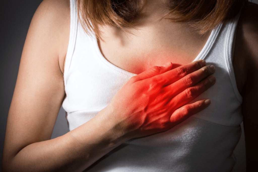 Uma mulher com a mão no peito e sintomas de infarto