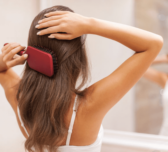 Mulher escovando cabelo depois de saber o que é bom para queda de cabelo