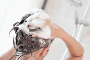 Pessoa lavando o cabelo com shampoo para cabelo oleoso
