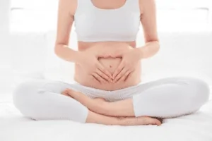 Foto de uma mulher sentada fazendo um coração com a mão com 34 semanas de gestação