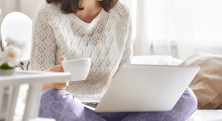 Pessoa em atendimento com psicologos online enquanto segura um notebook e uma xícara de chá