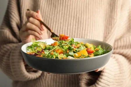Uma pessoa segurando um prato cheio de alimentos ricos em potassio