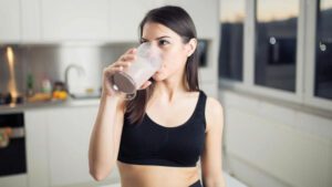 imagem com uma mulher tomando suplemento para engordar