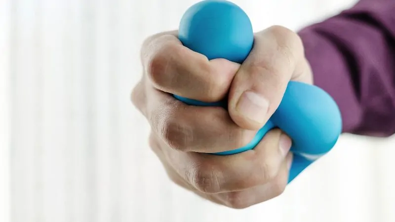 imagem com uma mão apertando uma bolinha anti stress
