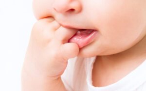 Criança colocando a mão na boca