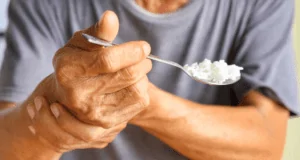 Pessoa com tremor no corpo tentando comer