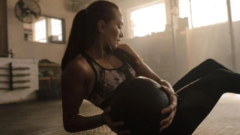 mulher praticando exercício abdominal russo para afinar cintura