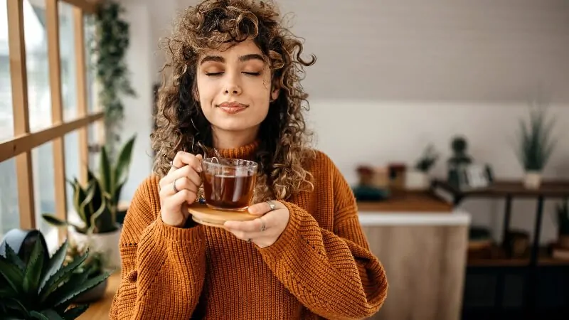 imagem com uma mulher tomando chá para desinflamar o corpo