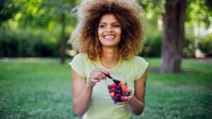 imagem de uma mulher comendo frutas vermelhas para desinflamar o corpo