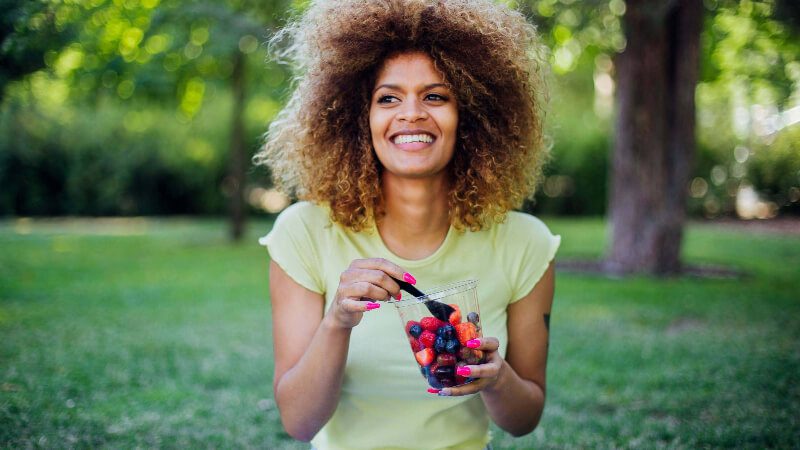 imagem de uma mulher comendo frutas vermelhas para desinflamar o corpo
