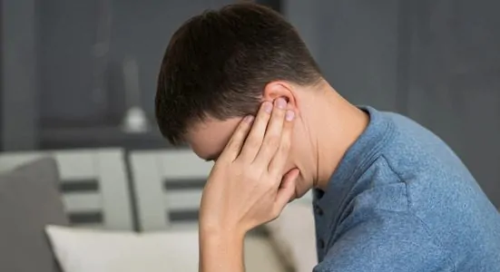 Homem com mão no ouvido sentindo uma pontada no ouvido