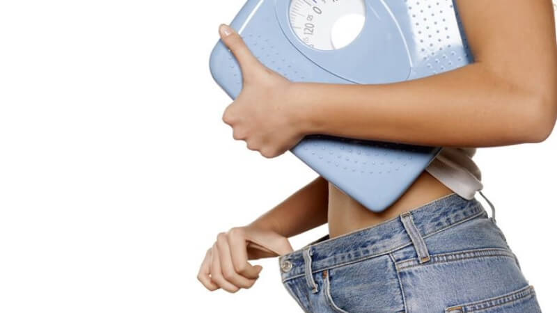 imagem de uma mulher segurando uma balança para calcular seu peso