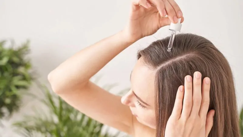 imagem com uma mulher aplicando tônico para crescer cabelo