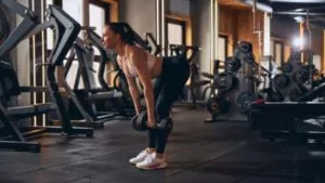 imagem com uma mulher realizando o exercício stiff com halteres