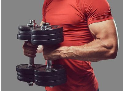 Homem malhando na academia enquanto segura dois halteres