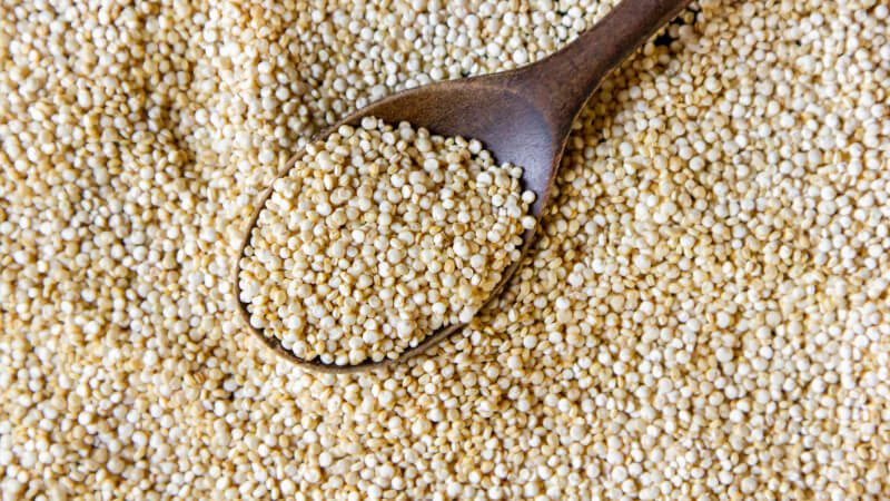 Imagem com uma colher de pau com Quinoa em grãos