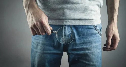 Homem com caroço no saco escrotal usando uma lupa