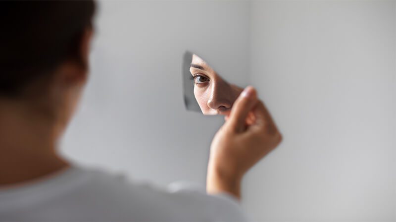 Imagem de uma mulher com narcisismo se olhando no espelho