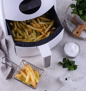 Air fryer com batatas fritas prontas dentro da bandeja
