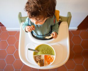 criança comendo em cadeira de alimentação