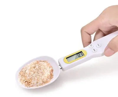 imagem de uma mão segurando uma colher medidora digital da T.G.Y