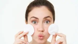 imagem de uma mulher segurando dois algodões no rosto