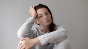 imagem de uma people pleaser pensativa com a mão na cabeça