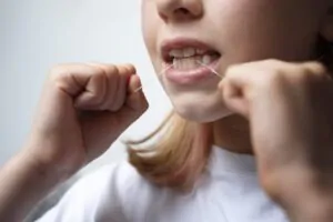 Menina aprendendo como usar fio dental corretamente