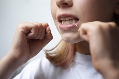 Menina aprendendo como usar fio dental corretamente