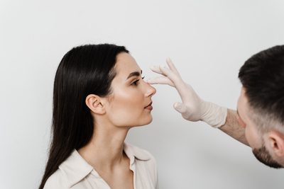 Homem examinando nariz de mulher