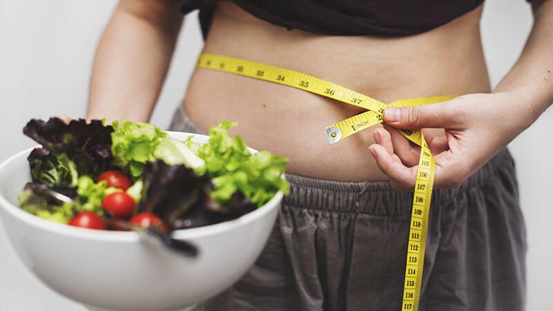 imagem de uma mulher medindo a cintura após fazer dieta