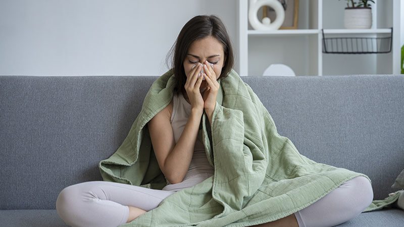 imagem de uma mulher sentada no sofá com sinusite
