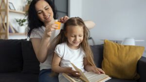 imagem de uma mulher realizando o tratamento usando pente fino e remédio para piolhos para acabar com a infestação na filha