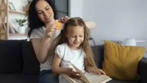 imagem de uma mulher realizando o tratamento usando pente fino e remédio para piolhos para acabar com a infestação na filha