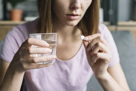 Mulher tomando remédio para dor no músculo