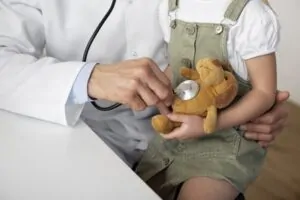 Médico com criança no colo investigando a síndrome de highlander