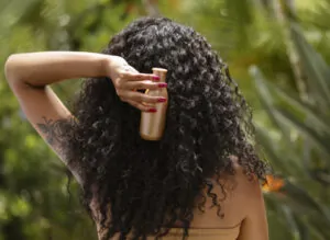 mulher segurando shampoo para cabelo cacheado