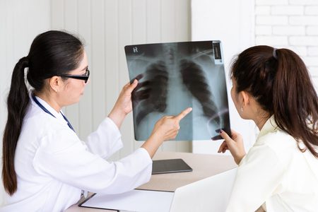 Mulher com sintomas de pneumonia olhando seu raio X junto a uma médica